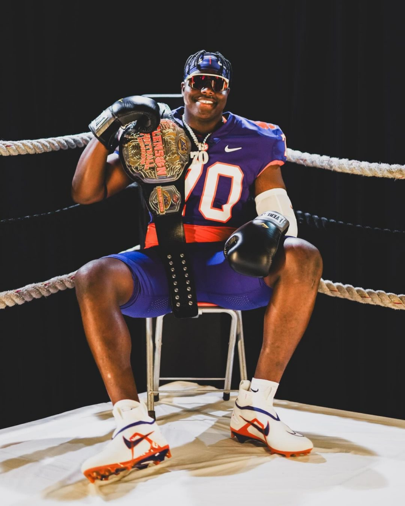 ˛David Sanders Jr. commitment clemson picture of him in a wresltling ring with a Clemson title belt